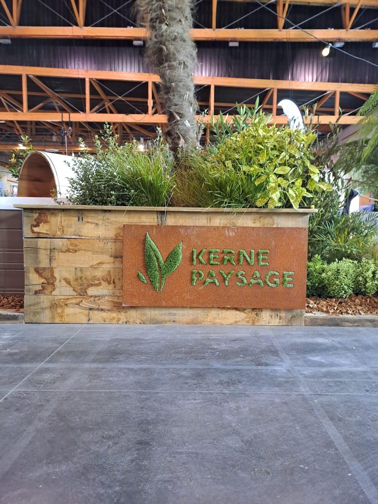 Plaque acier corten avec inscription Kerne Paysage gazon synthétique sur jardinière en bois