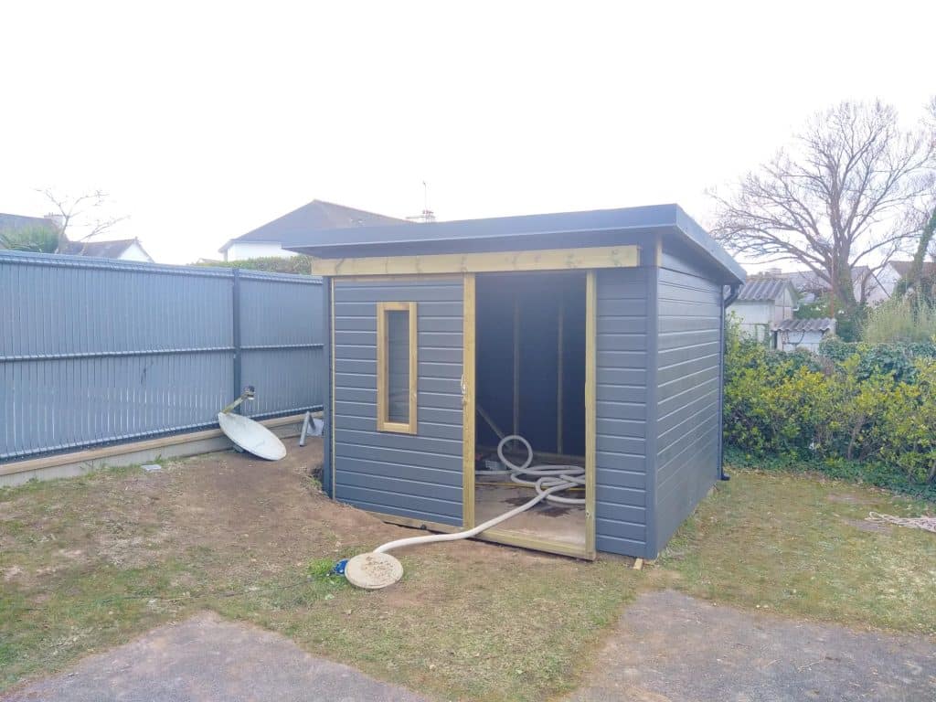 Abri en bois coloré sur-mesure avec porte coulissante et fenêtre