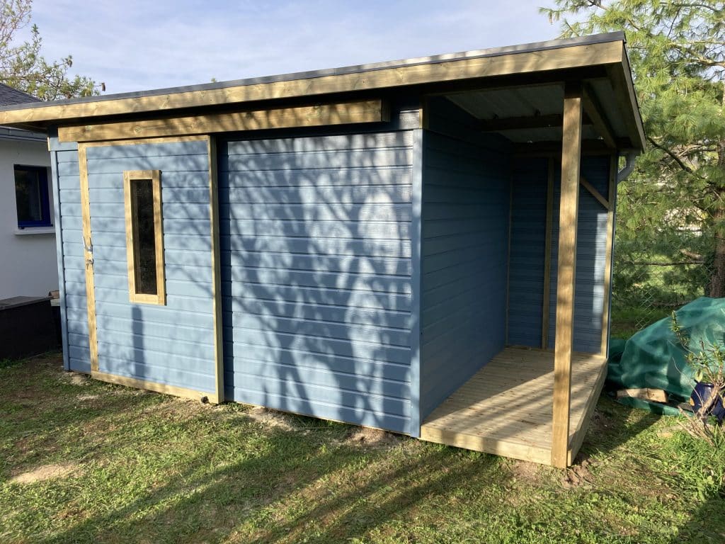 Abri en bois coloré sur-mesure avec porte coulissante, fenêtre et bucher