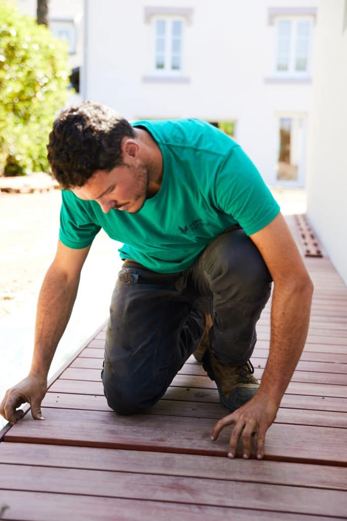 Nicolas posant une lame de bois sur un platelage grad