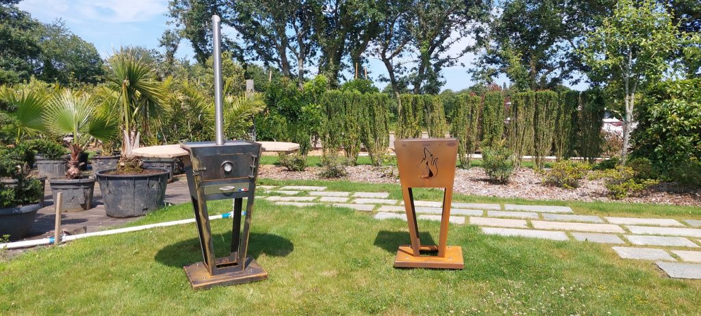 Présentation des braseros TOUSSAINT dans l'espèce showroom de la pépinière, devant des végétaux.