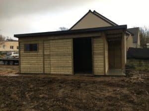 Abri en bois sur-mesure avec porte coulissante, fenêtre et bûcher