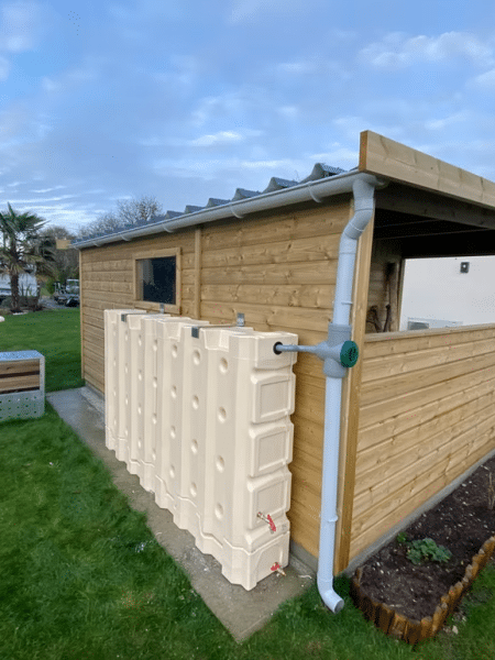 Abri en bois avec un bac de récupération d'eau relié à une goutière
